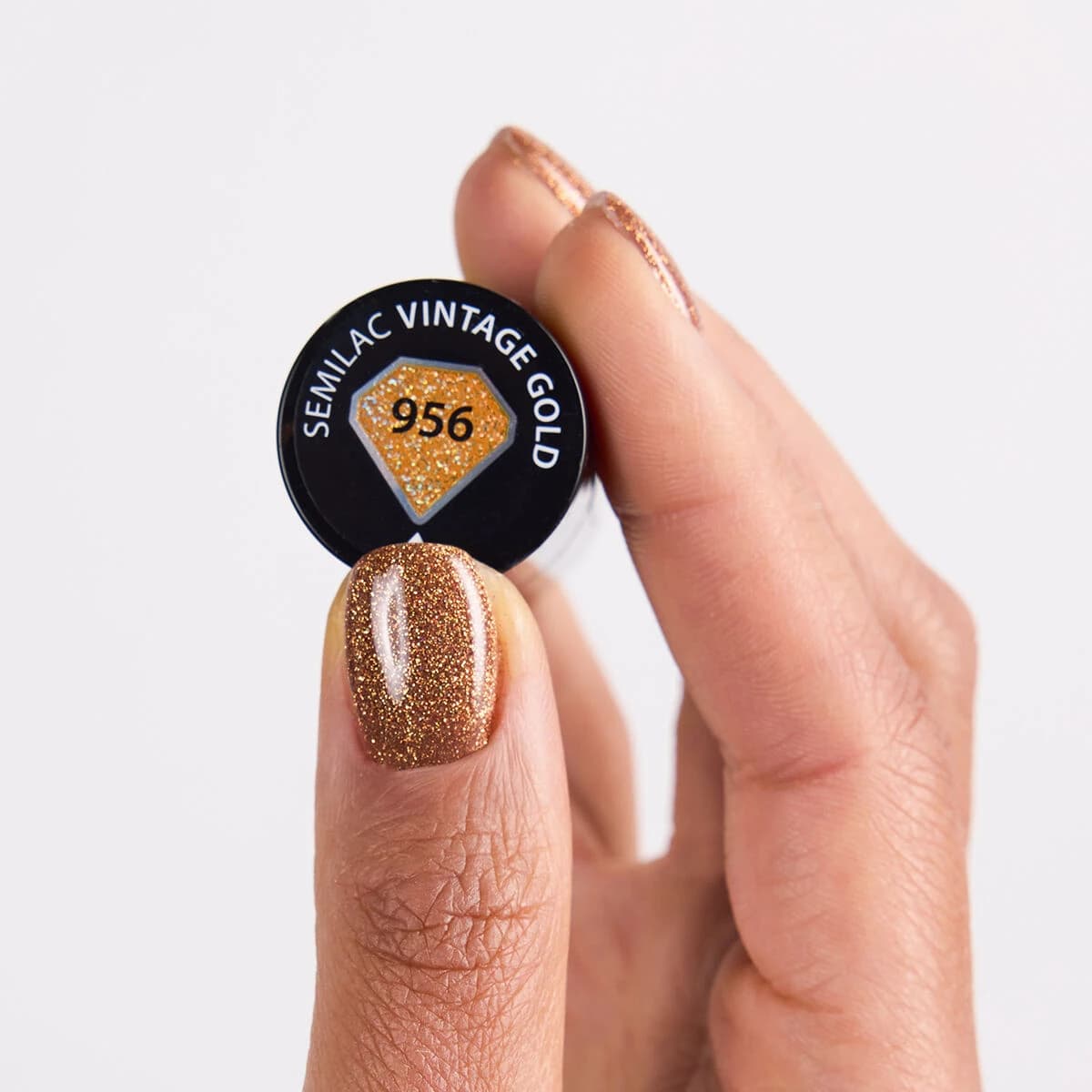 Flacon et swatch du Semilac – Vernis semi-permanent 956 Vintage Gold. c’est un doré intense façon or liquide, sublimé par un effet holographique sophistiqué.